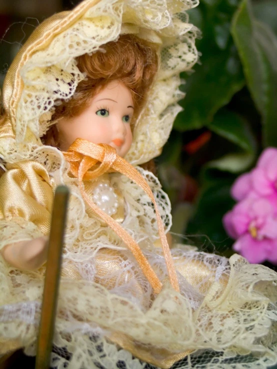 a doll sits in a lacy umbrella with a cane