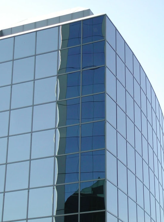 a building reflecting it's glassy side with a clear sky in the background