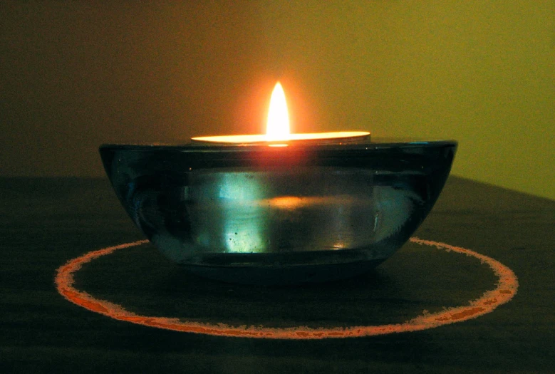 a lit candle inside of a black glass bowl