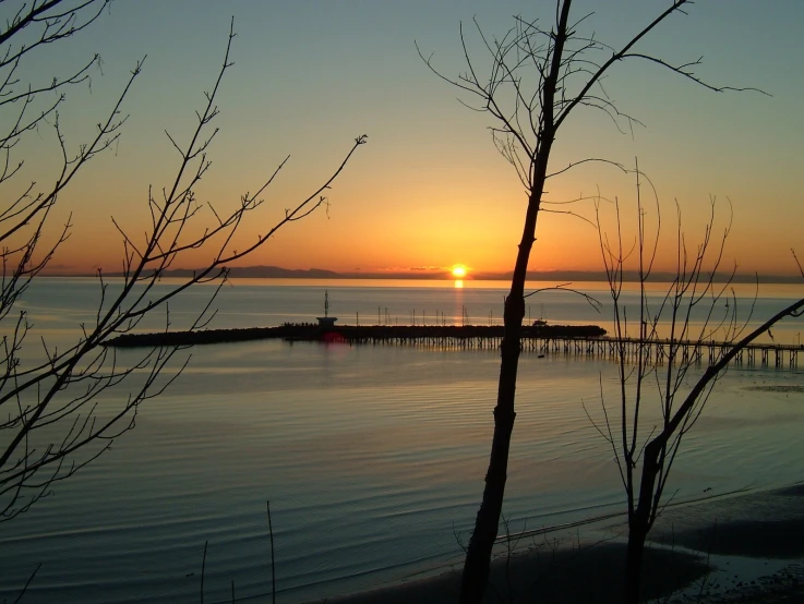 the sun is setting over the water off shore