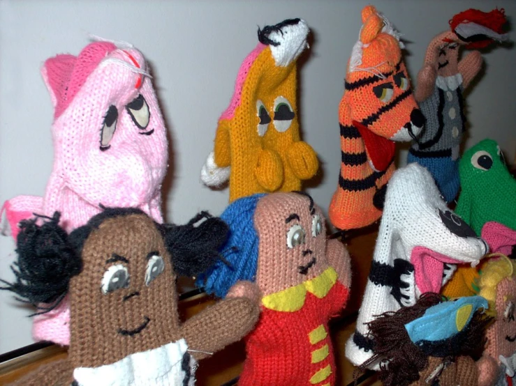 many different knitted stuffed animals with eyes and arms