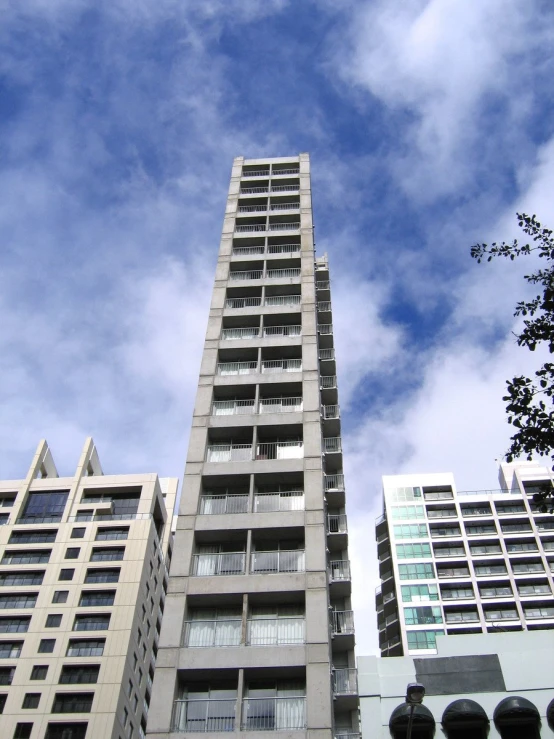 three tall buildings on a cloudy day against the sky