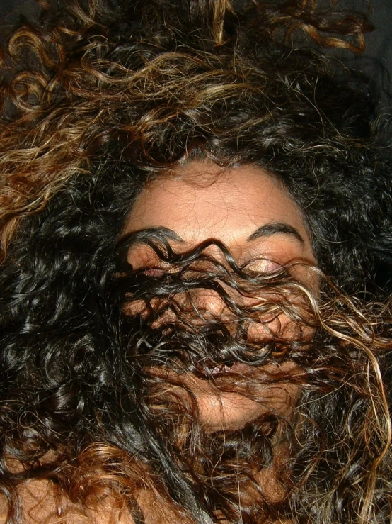 a woman with curly hair covering her face