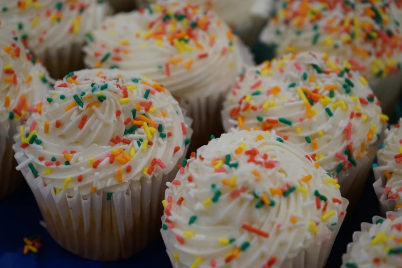 cupcakes with icing, sprinkles and confetti on a blue plate