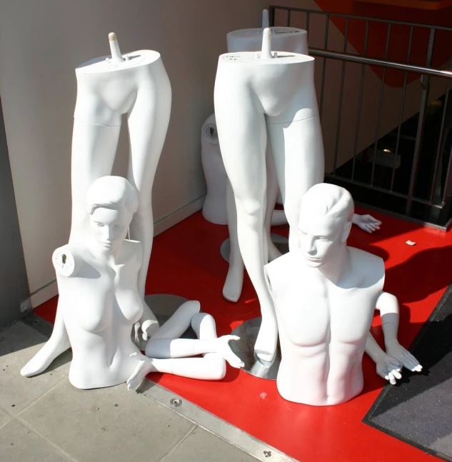 a group of white dummy standing next to each other on top of a red carpet
