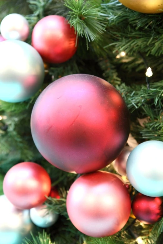 close up s of christmas balls hanging from the nches