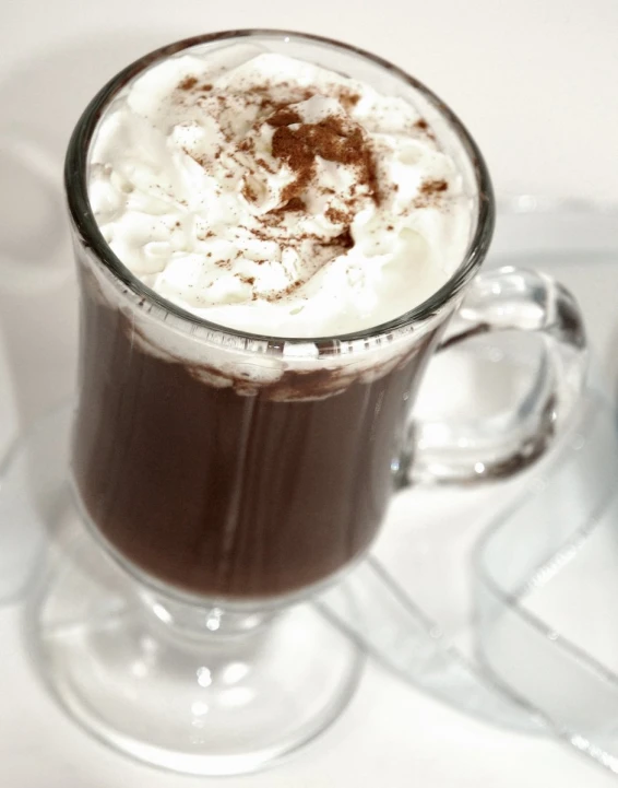 a clear cup with white foam and dark drink mix