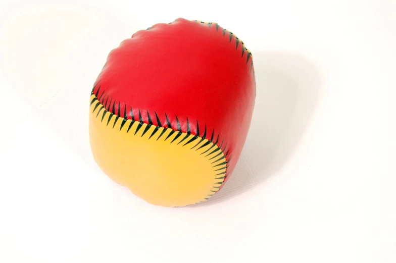 a red leather ball with yellow stitchs on a white surface