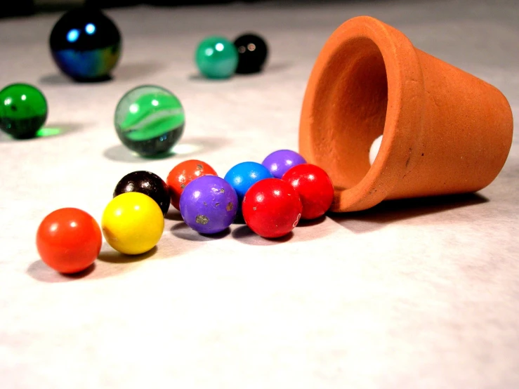 some colorful marbles are scattered near an orange cup