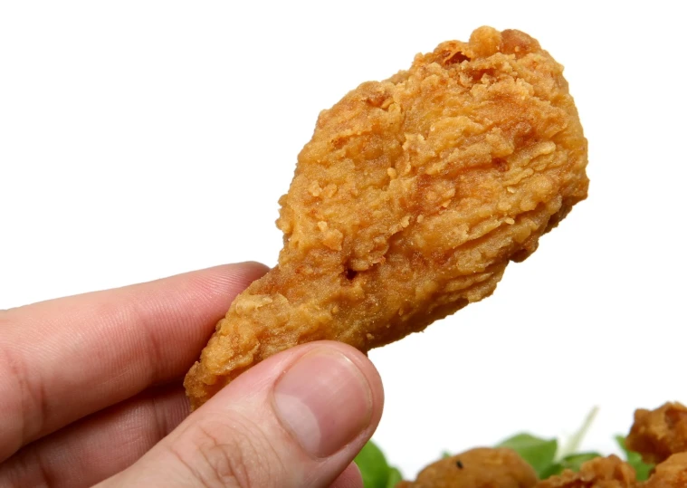 a hand holding a fried chicken next to another item
