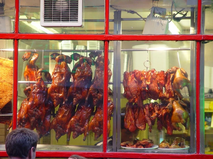 a man watching some chickens hanging up outside a store