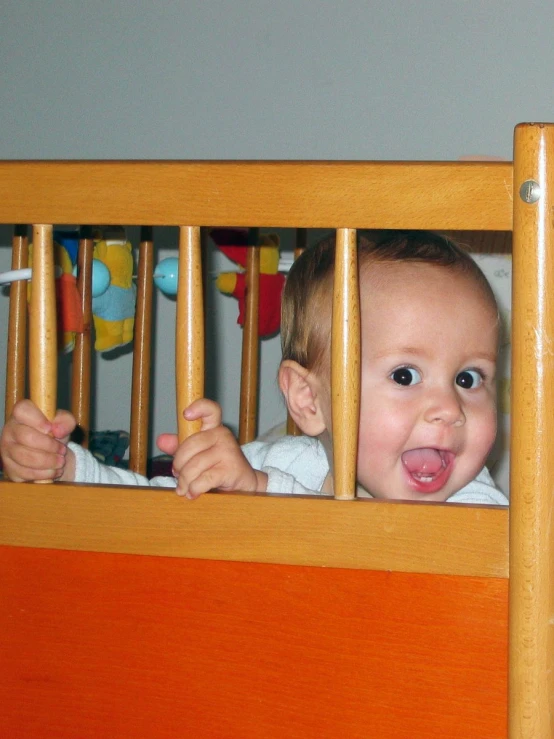 a baby in a crib with a toy behind him