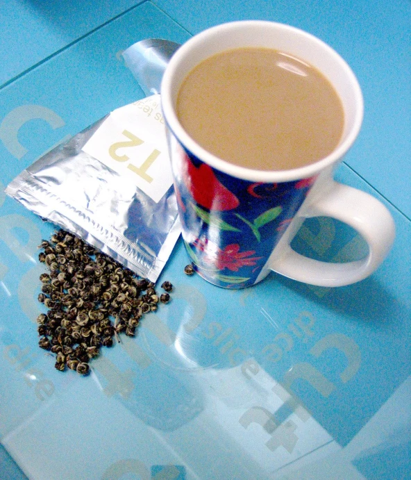 a tea bag on the table and an empty coffee cup next to it