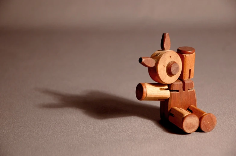 a wooden toy bear is sitting and posing