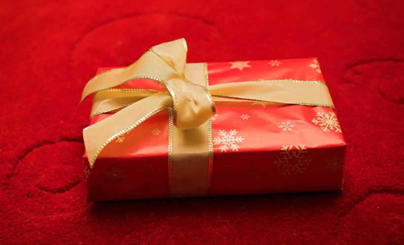 the wrapped present is sitting on the red cloth