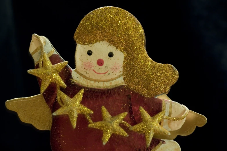 a glass ornament with gold stars in the form of a girl holding a star