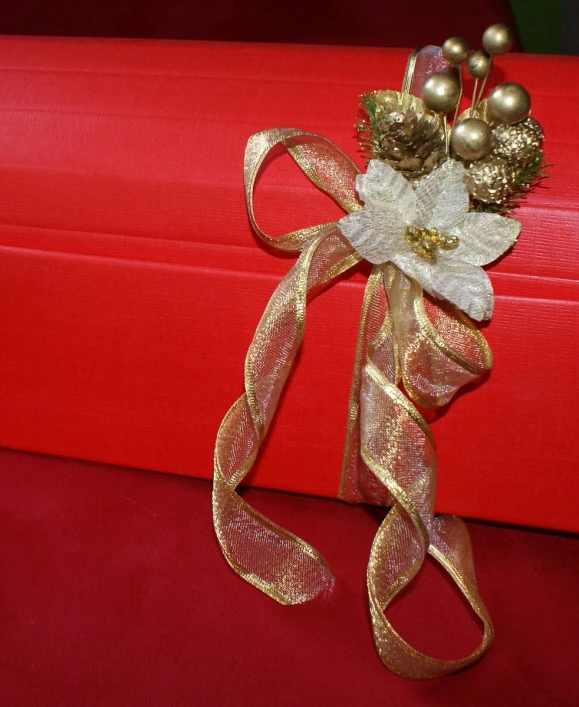 a gold ribbon with flowers and ornaments tied around it