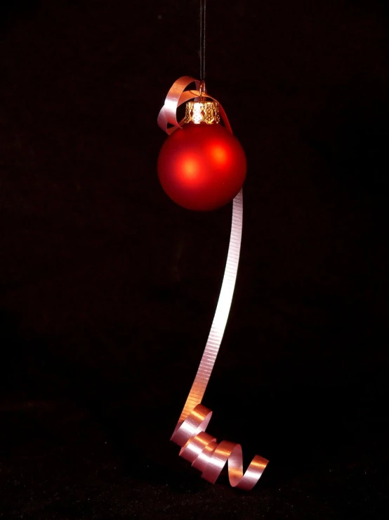 a red ornament hanging on a silver ribbon