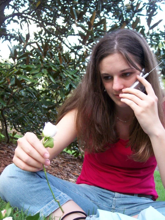 a girl sitting outside talking on her cell phone