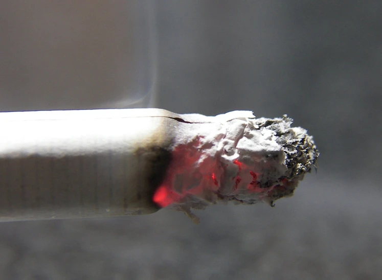 closeup po of a cigarette smoking red and grey