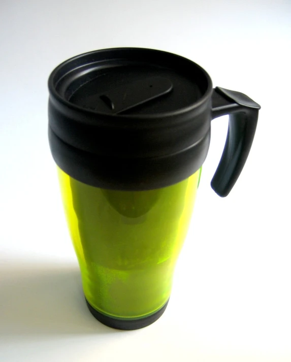 a yellow travel mug sitting in the sunlight