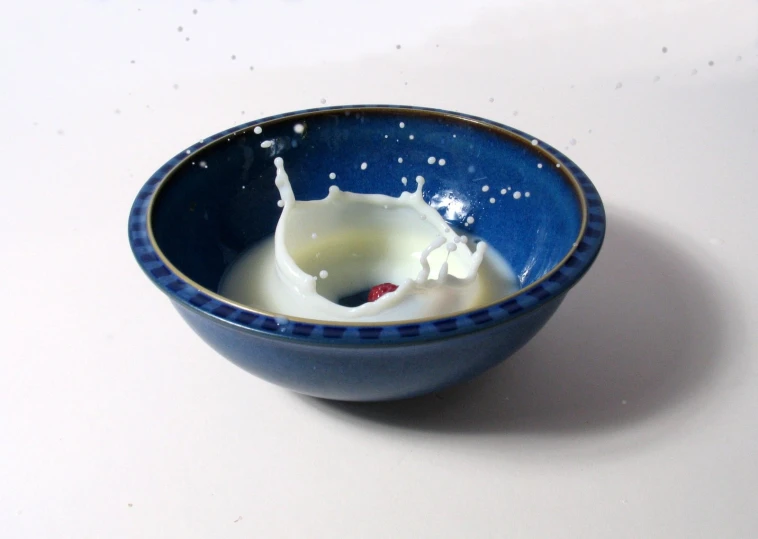 a milk splash is inside a small blue bowl