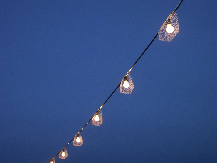 string lights with circular shaped bulbs hang against a deep blue sky