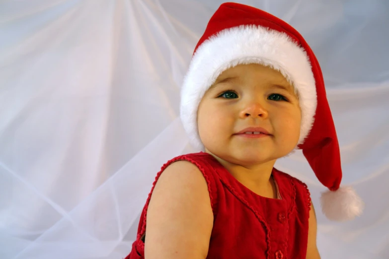 an infant wearing a santa hat and a red dress