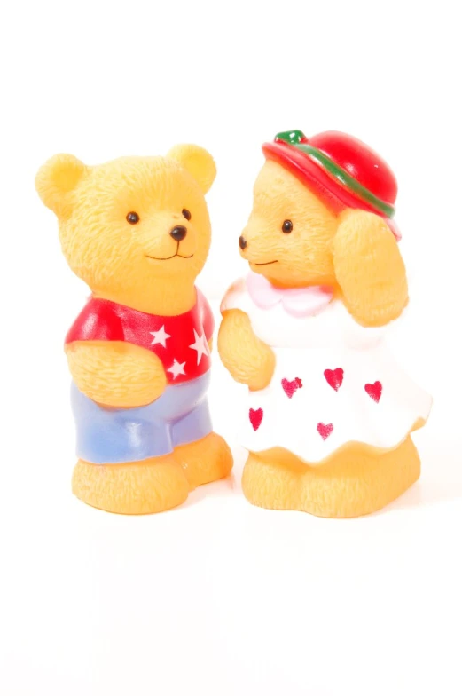 two teddy bears one wearing a red hat the other yellow