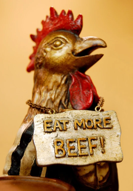 a chicken is holding a sign that reads eat more beef