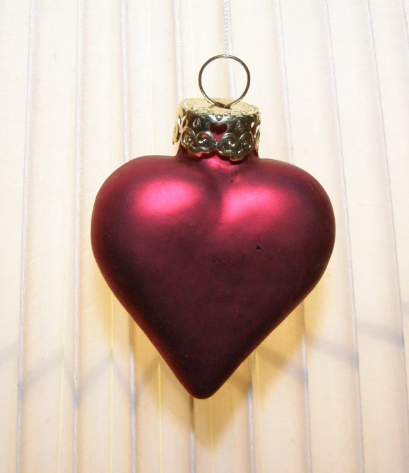 a red heart with a ring hanging from it