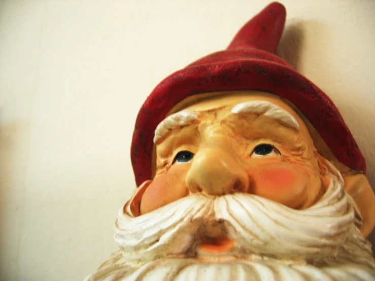 a small garden gnome's head against a white wall