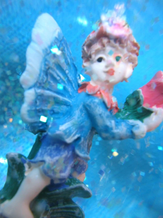 a glass angel figurine with blue dress and wings
