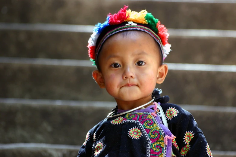 little boy dressed up in a sweater and colorful head band