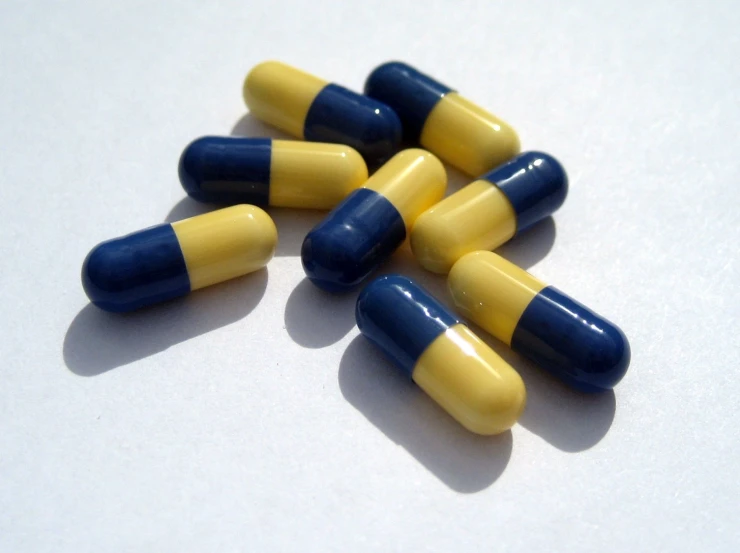 several yellow and blue pills on a white background