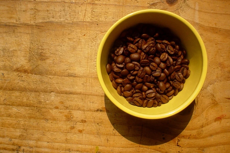 the yellow bowl is full of coffee beans