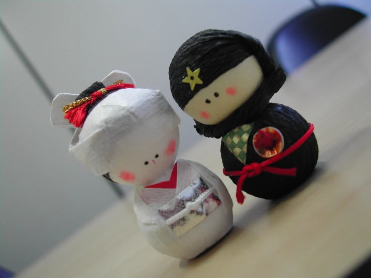 two dolls sitting side by side in front of a computer mouse