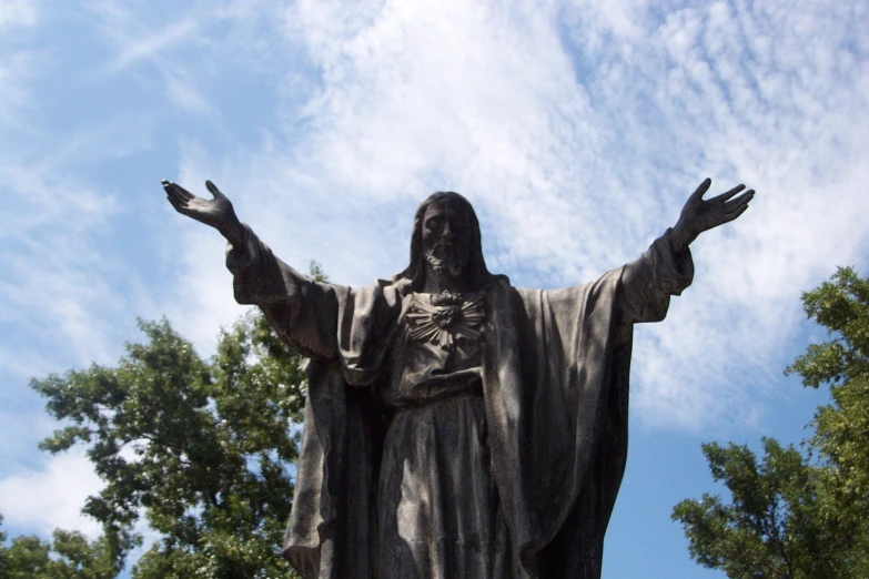 a statue in front of trees and blue sky