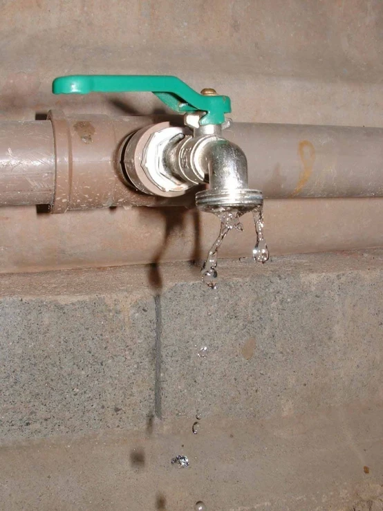 an old style metal faucet with a green handle attached to it