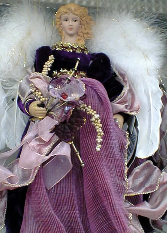 a doll is sitting on a table with white and purple dress