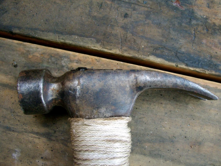 an old hammer attached to a rope on a piece of wood