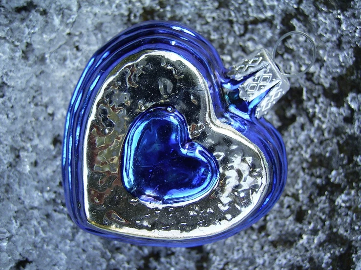 a glass heart with a diamond inside sitting on some rocks