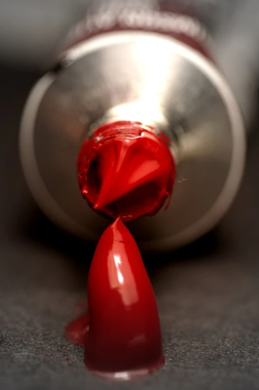 red liquid pouring out from bottle onto grey surface