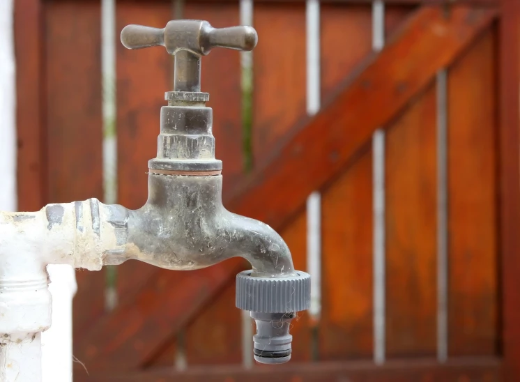 water spigot coming from the side of a wooden fence