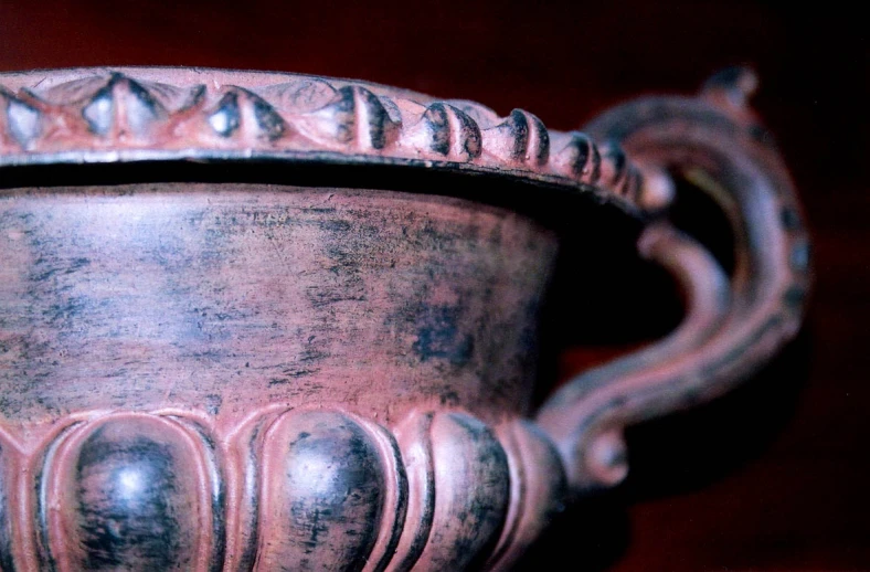 a carved clay vase on a shelf on display