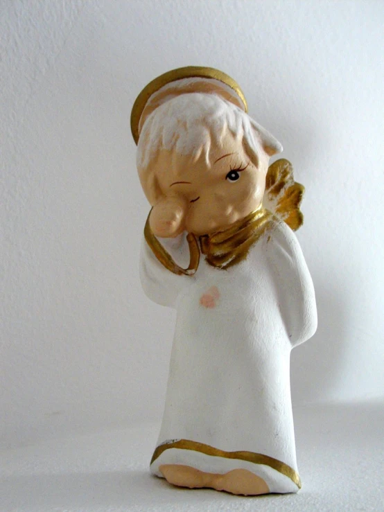 a white and gold figurine of a person wearing white clothes