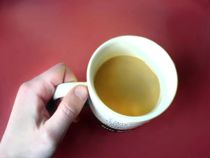 a person is holding a coffee mug full of tea