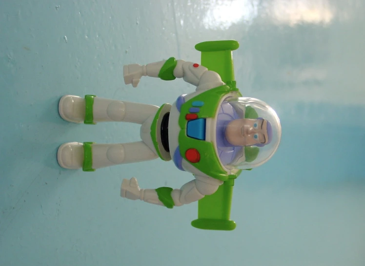 a green toy spaceship flying past a blue background