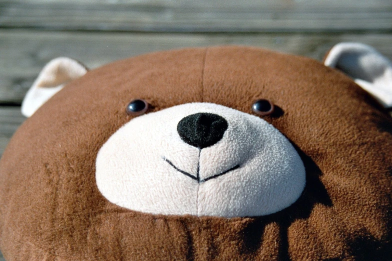 a close up of a stuffed bear on a wooden bench