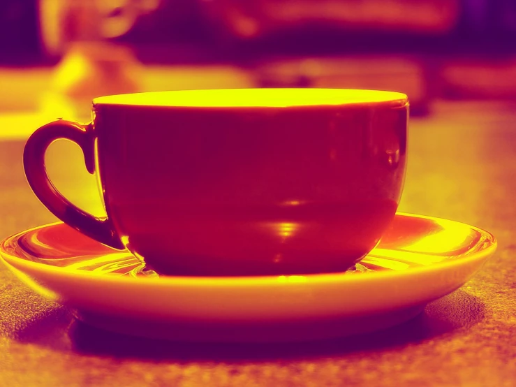 a coffee cup sits on the edge of a yellow plate